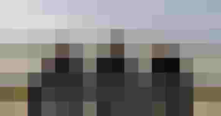 Drei Personen sitzen auf Bank am Seeufer