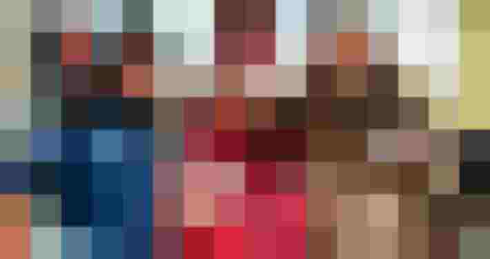 Drei Personen an einem Wintermarktstand lächeln und halten Becher