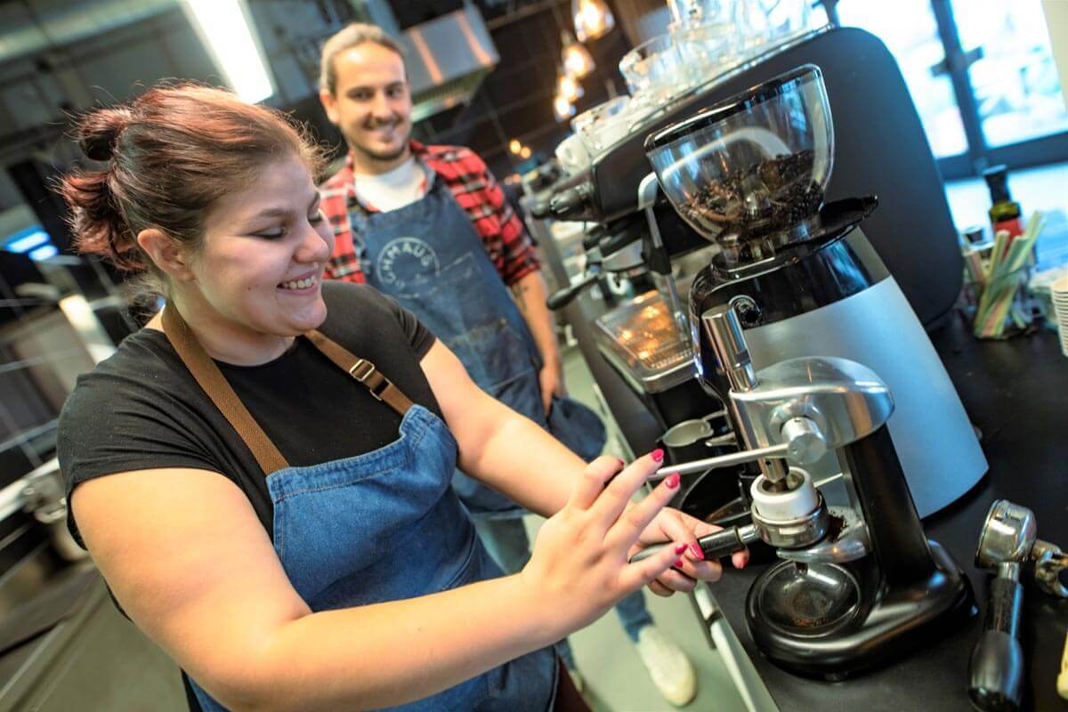 Zwei MitarbeiterInnen im Schmaus & Browse bei der Zubereitung einen Kaffees.