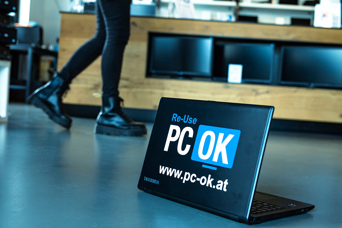 Geöffneter Laptop mit Logo von PC-OK auf dem Deckel.