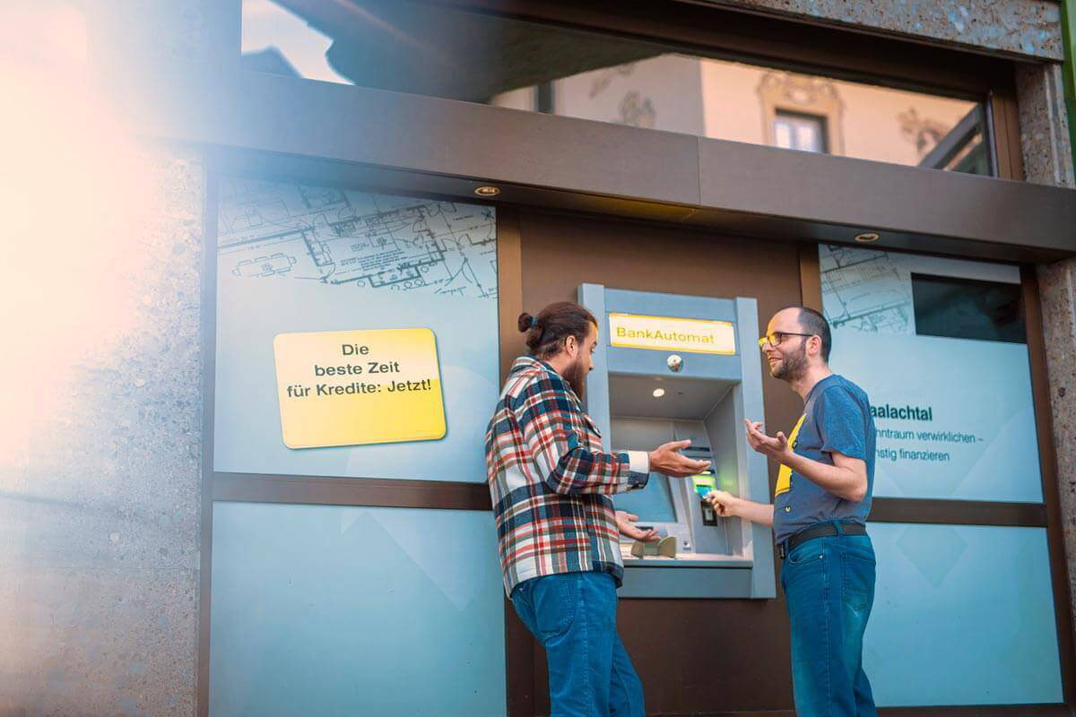 Ein Betreuer unterstützt einen Bewohner bei seinen Bankgeschäften am Bankautomat.