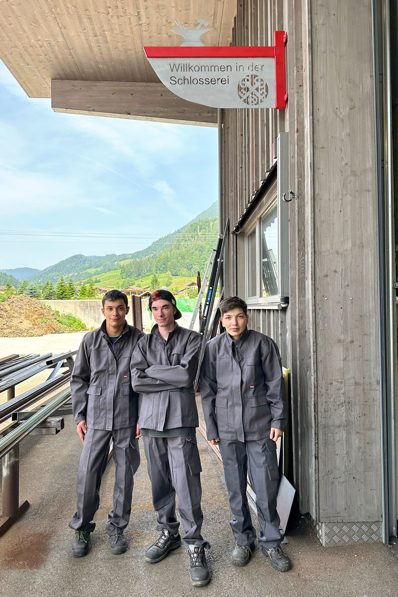 Drei Jugendliche stehen unter dem neuen Zunftzeichen der Schlosserei am Campus oberrainanderskompetent