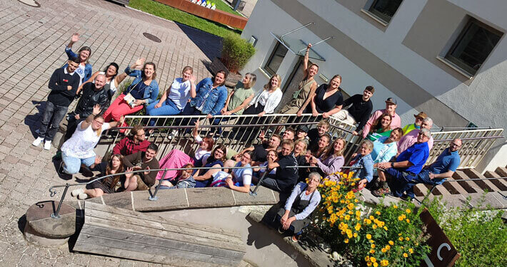oberrainanderskompetent_Abschlussfeier_2023_Gruppenfoto_Beitrasgbild Gruppenfoto der Jugendlichen und MitarbeiterInnen von oberrainanderskompetent auf einer Treppe sitzend
