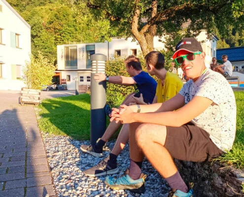 Drei Jugendliche sitzen in der Sonne am Campus von oberrainanderskompetent