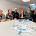 Team des Sozialunternehmens und Team vom AMS Salzburg vor dem Modell des Kreativraums.