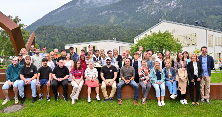 Gruppenfoto Abschlussfeier 2025 vor moderner Architektur und Bergen, inklusive Teilhabe
