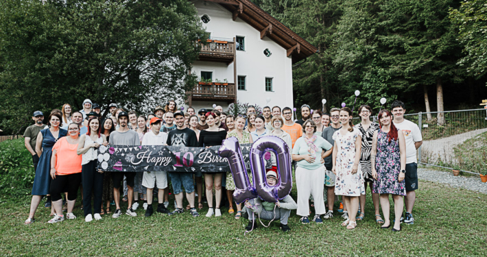 Gruppe von Menschen feiert Jubiläum im Freien vor Haus