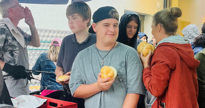 Menschen stehen bei einer Grillfeier mit Semmeln in der Hand